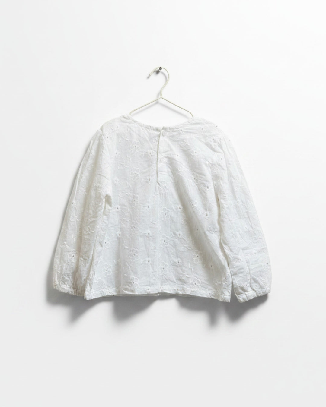 Blusa blanca Kankla de manga larga con bordado floral y botones en la espalda.