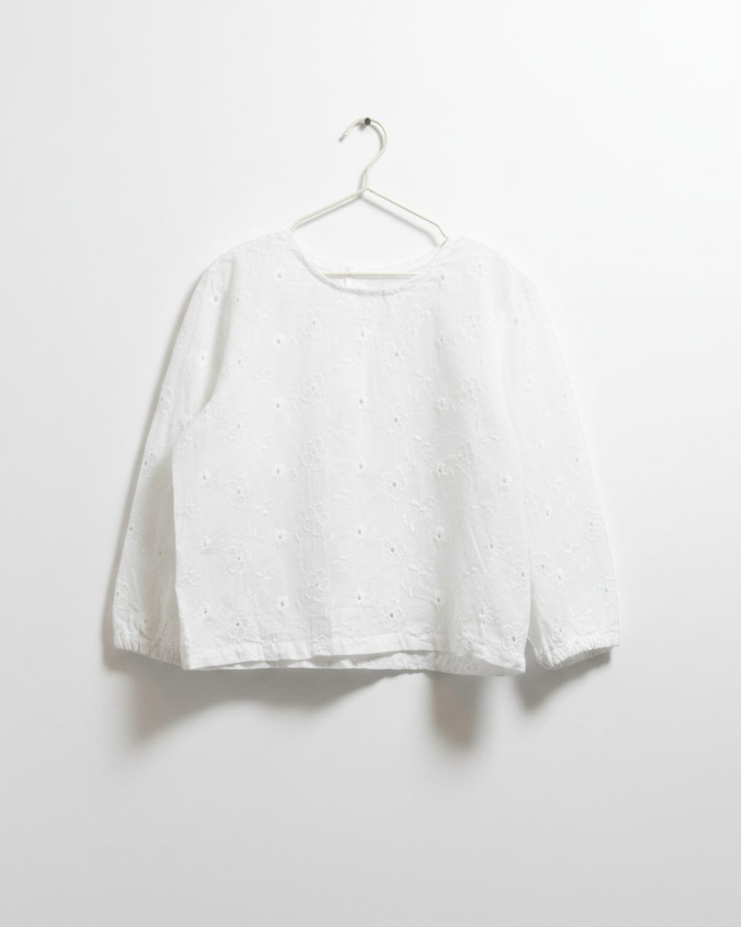 Blusa blanca Kankla de manga larga con bordado floral y botones traseros.
