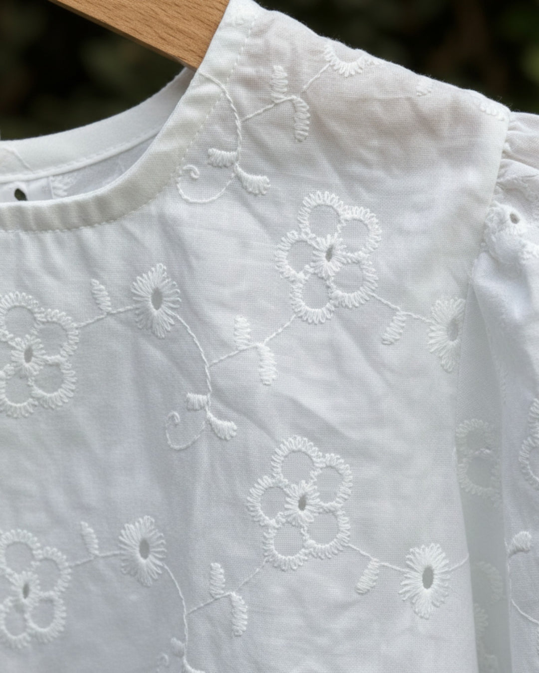 Blusa blanca Kankla de manga larga con bordado floral y elástico en puños. Cierre de dos botones en la espalda.