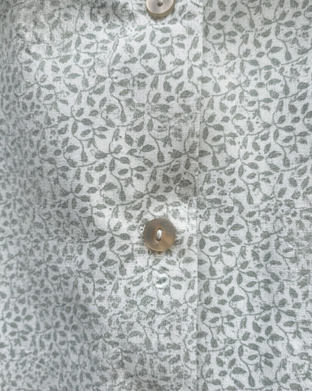 Blusa Kankla de algodón 100% con estampado de hojas grises y botones frontales.