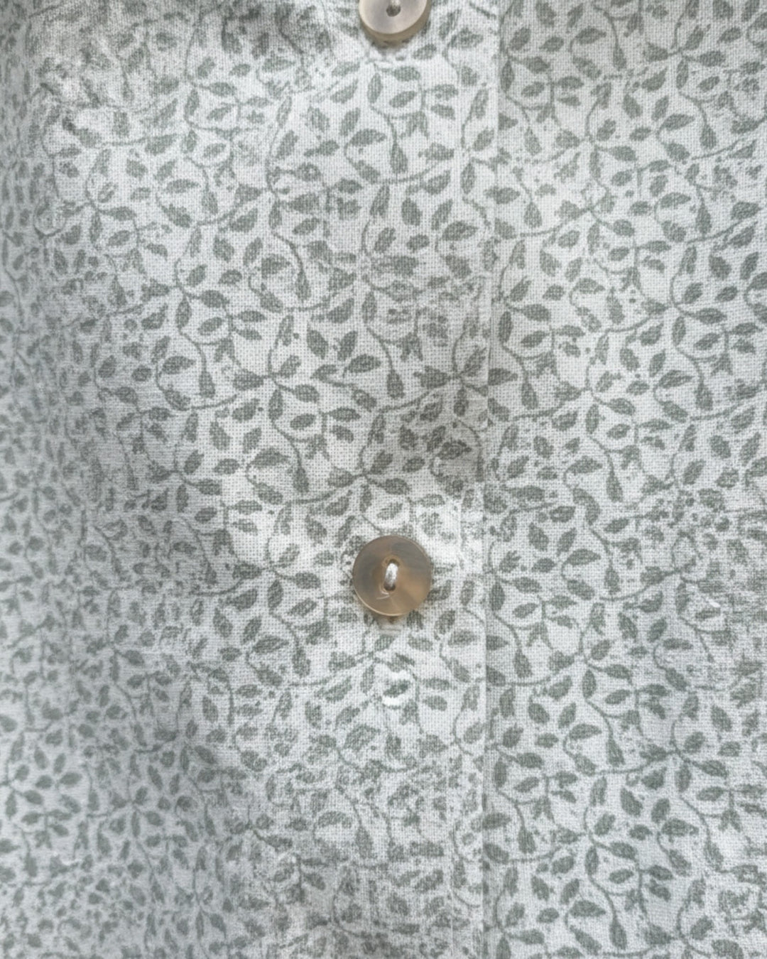 Blusa Kankla de algodón 100% con estampado de hojas grises y botones frontales.