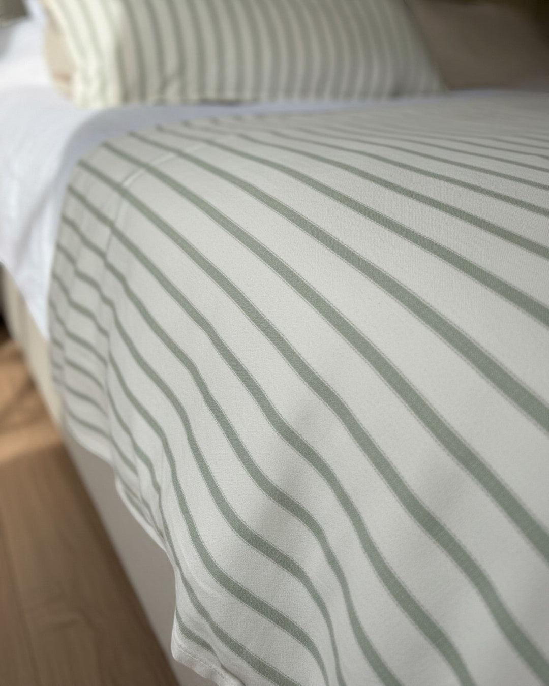 Piecera reversible Kankla de algodón con diseño de rayas verdes y blancas sobre una cama, incluye relleno removible.