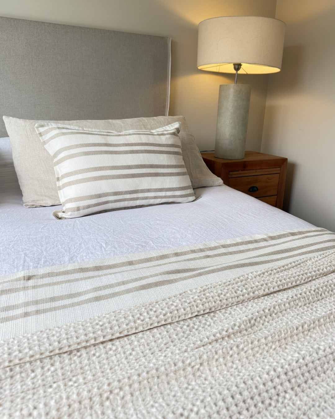 Piecera Kankla Mónaco reversible de algodón a rayas y lino beige con relleno removible sobre cama