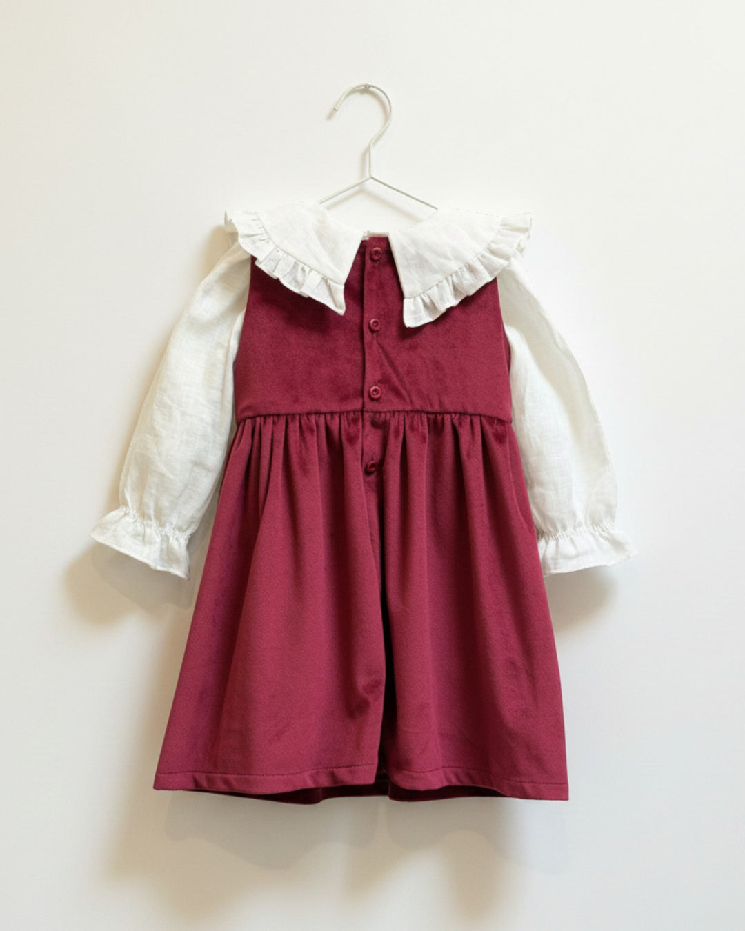 Vestido Kankla de terciopelo rojo sin mangas con cuello blanco de lino y volantes. Cierre de botones.